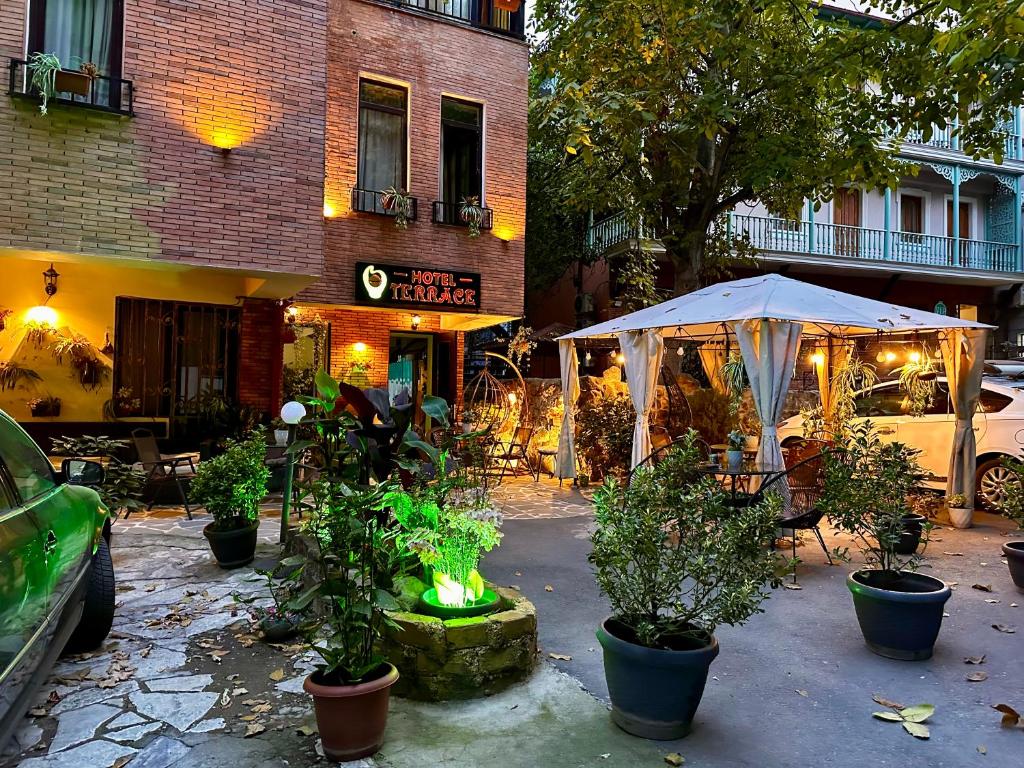 eine Terrasse mit Pflanzen und einem Sonnenschirm vor einem Gebäude in der Unterkunft Terrace Tbilisi Center in Tbilisi City