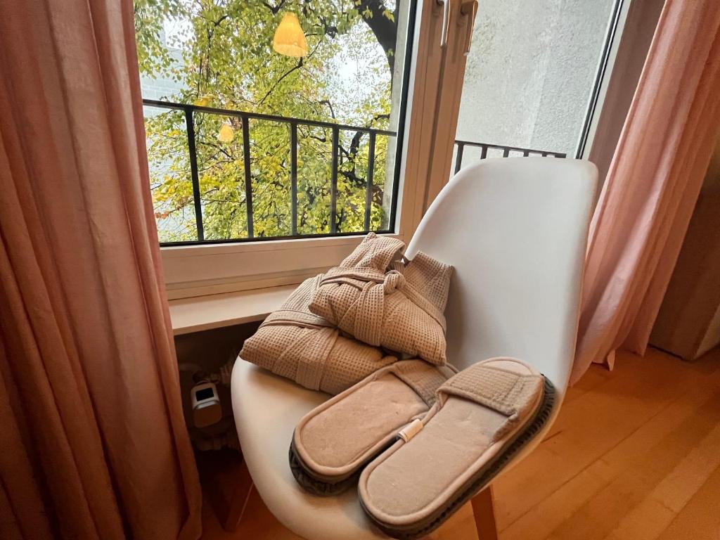 una silla blanca con sandalias sentada frente a una ventana en Feel home en Frankfurt