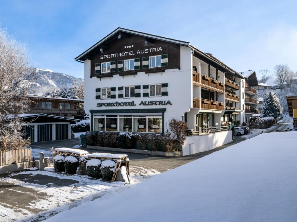 a building with snow on the ground in front of it at Sporthotel Austria in Sankt Johann in Tirol