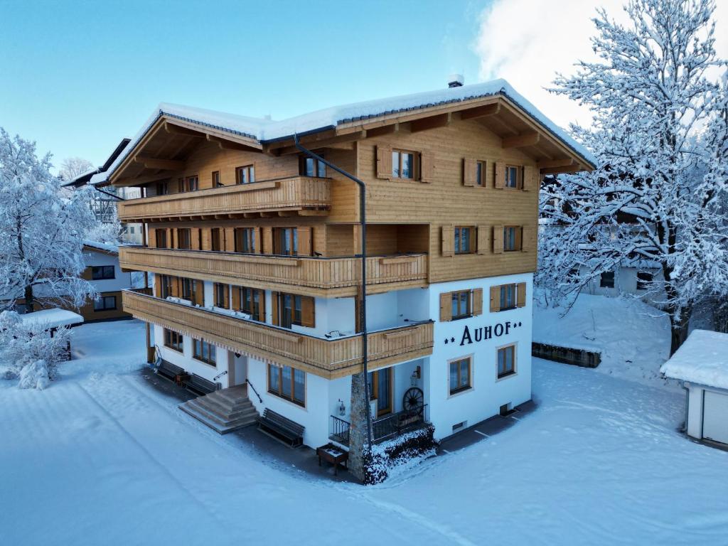 drewniany budynek z śniegiem na ziemi w obiekcie Appartement Pension Auhof w mieście Going