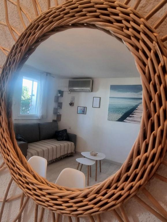 a living room with a wicker mirror on the wall at 100 m de la plage - Les Cigales de Mer - Studio Cabine - Parking in Le Grau-du-Roi
