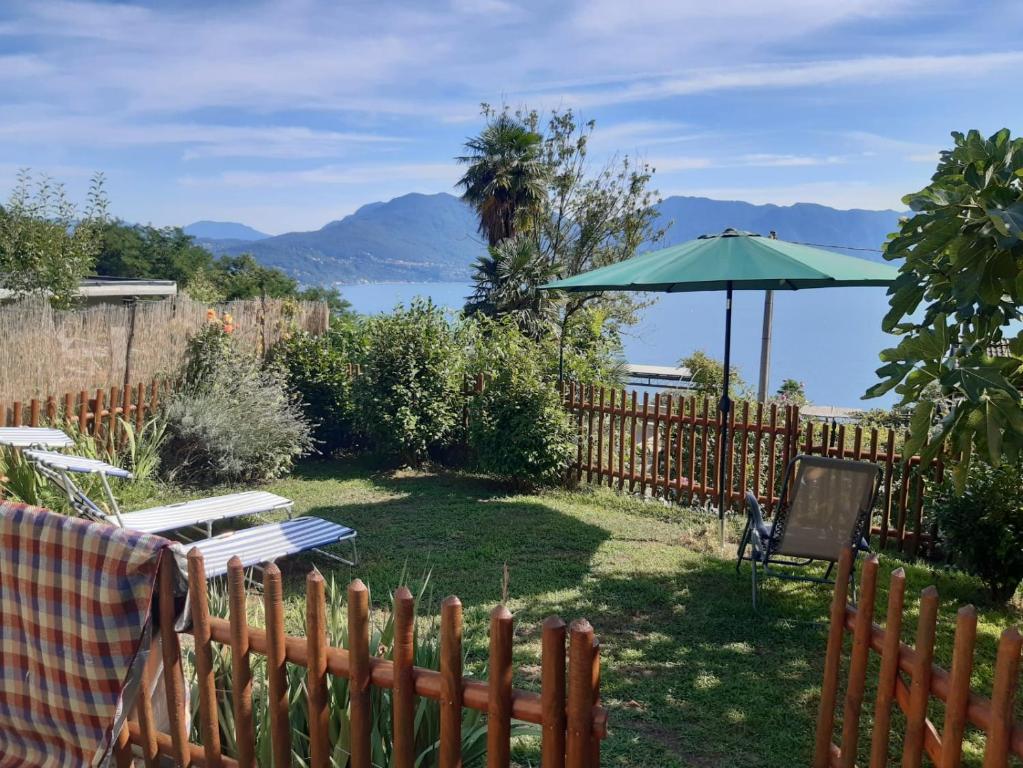 einen Garten mit einem Sonnenschirm, einem Tisch und Stühlen in der Unterkunft Casa giardino panoramico in Cannero Riviera