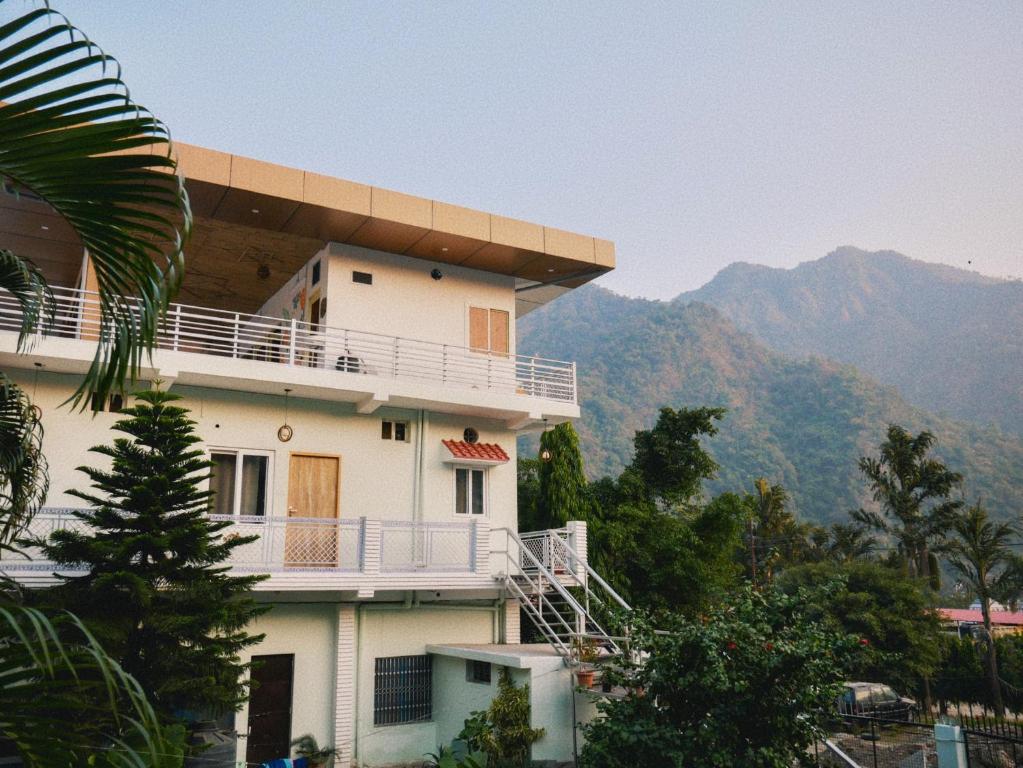 a building with a balcony and mountains in the background at Flow House in Rishīkesh