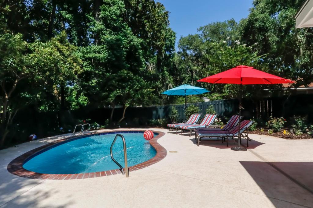 a swimming pool with two chairs and two umbrellas at 120 Druid Oaks Lane in Saint Simons Island