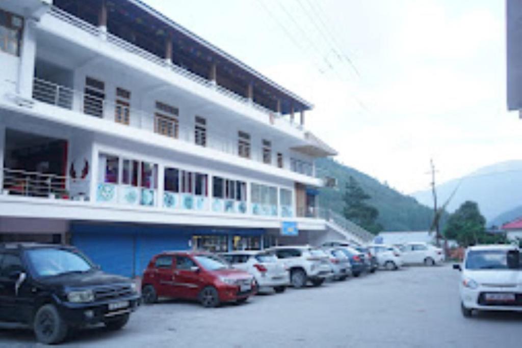 a parking lot with cars parked in front of a building at Hotel 7 Eleven Dirang in Dirang Dzong