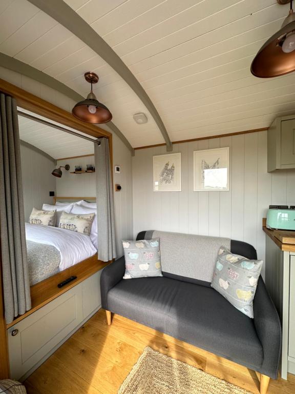 a bedroom with a bed and a couch and a mirror at Private and peaceful stay in a Luxury Shepherds Hut near Truro in Truro
