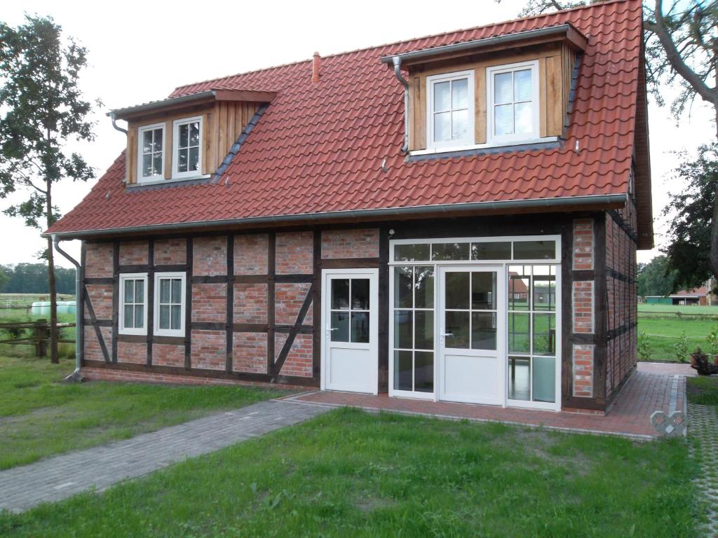 una pequeña casa con techo rojo y puertas blancas en Ferienhof Wikner, en Bruchhausen-Vilsen