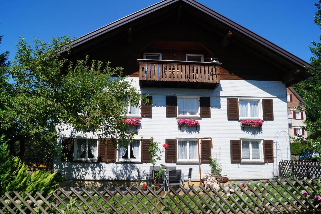 ein weißes Haus mit einem Balkon und einem Zaun in der Unterkunft Ferienhaus Lila in Hittisau