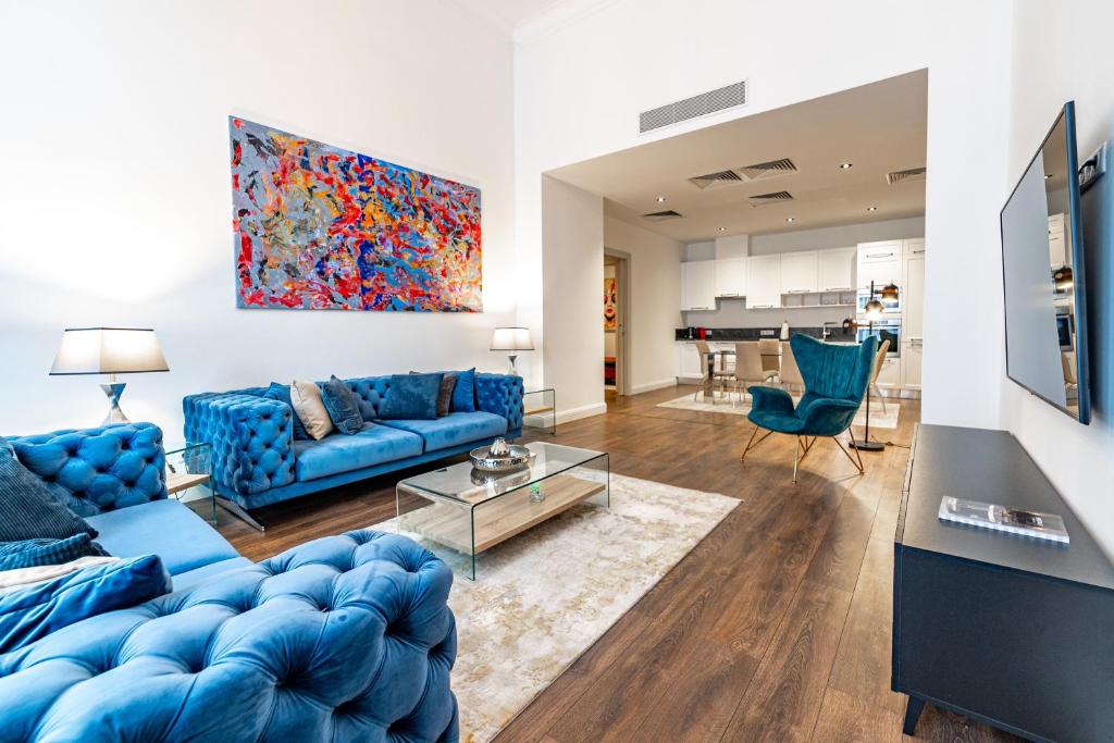 a living room with blue furniture and a painting on the wall at ZOYA LUXURY RESIDENCE in Budapest