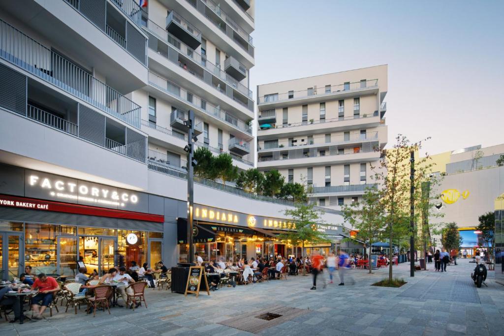 eine Stadtstraße mit Leuten, die vor einem Gebäude sitzen in der Unterkunft Appartement design d’architecte in Massy