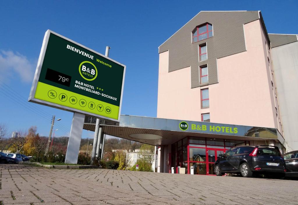 una señal frente a un edificio con un concesionario de automóviles en B&B HOTEL Montbéliard-Sochaux en Sochaux
