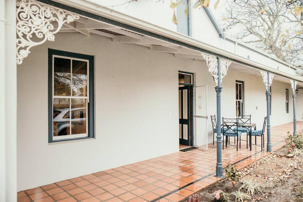 een wit huis met een patio met een tafel en stoelen bij Die Stal at Antioch in Franschhoek