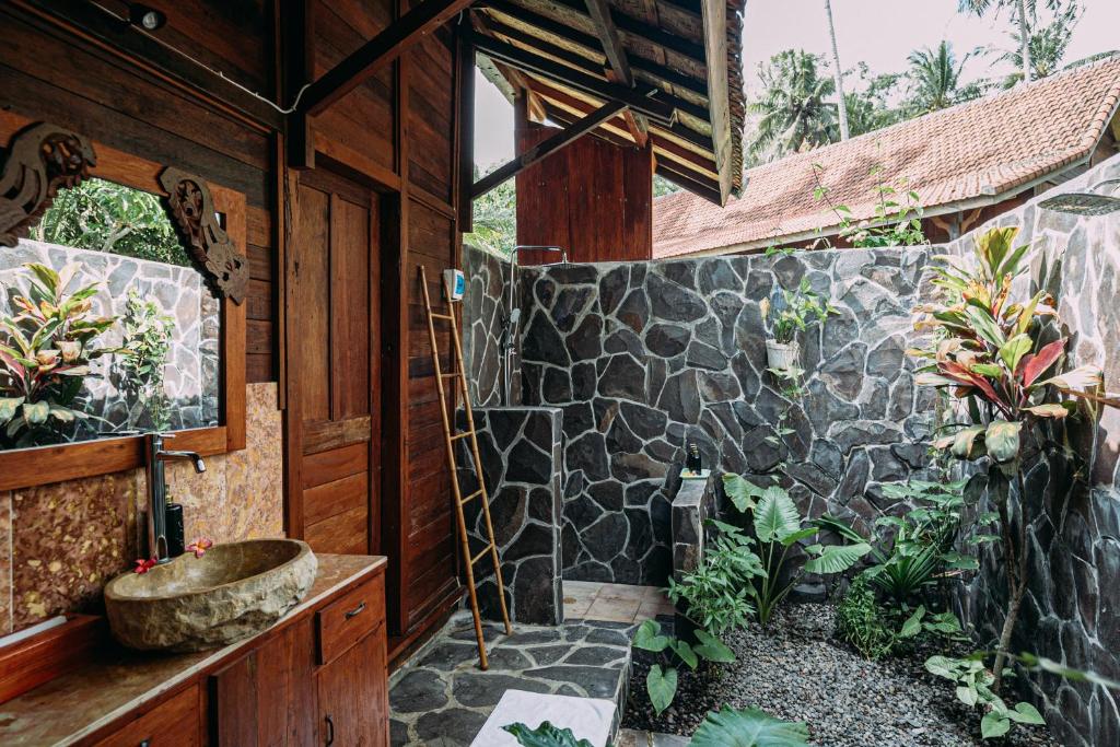baño con lavabo y pared de piedra en WOODEN HOUSE CANDIDASA en Manggis