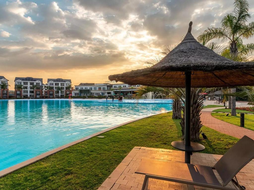 a resort swimming pool with a umbrella and a chair at The Blyde - Posh Living in Pretoria