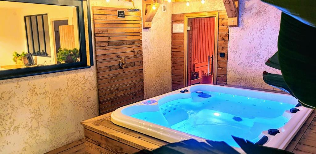 een badkamer met een bad en een spiegel bij Cocon Nature Montpellier - Jacuzzi & Sauna - 300m du Tramway in Castelnau-le-Lez