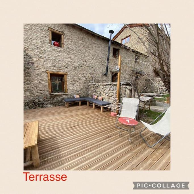 une terrasse en bois avec un banc et un bâtiment dans l'établissement L’Eterlou Authentique partie de corps de ferme 10pers., à Targassonne