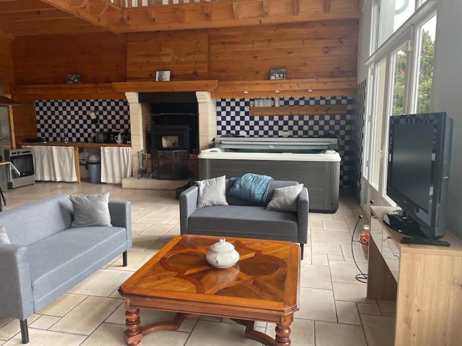 a living room with a couch and a tv and a table at Logement 6 personnes avec SPA in Essômes-sur-Marne