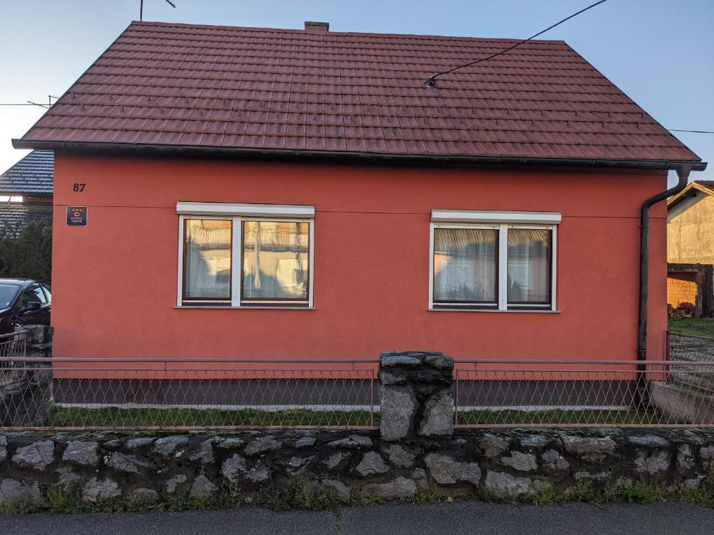 a red house with a stone wall at kuća za odmor Dolno in Sisak