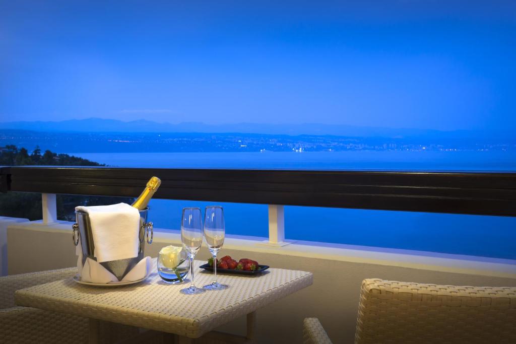 a table with wine glasses and a bottle on a balcony at Hotel Excelsior - Liburnia in Lovran