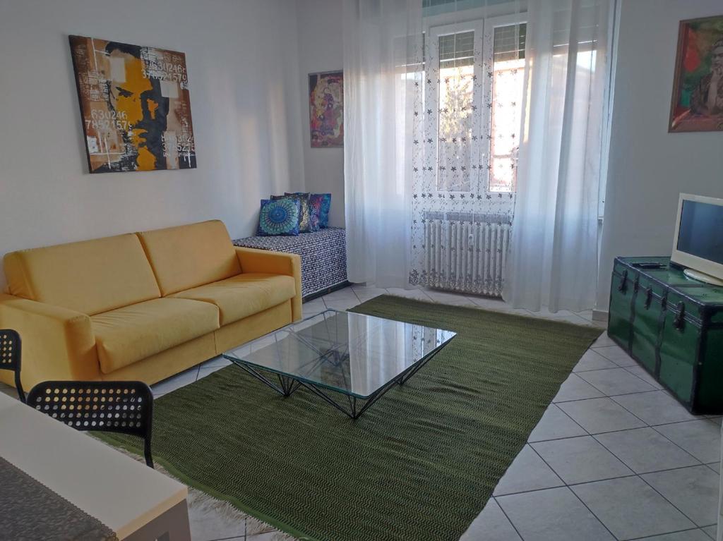 uma sala de estar com um sofá e uma mesa de café em vidro em Ca' Allegra - Centro em Asti