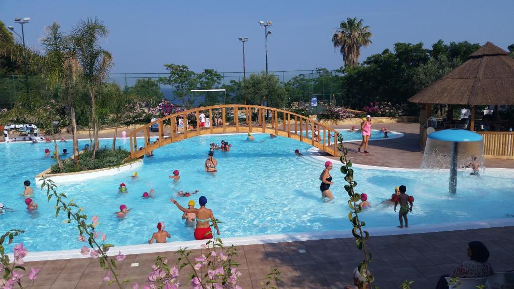 a group of people in a swimming pool with a bridge at Villaggio Marinella DIRETTAMENTE sul mare in Isola Capo Rizzuto