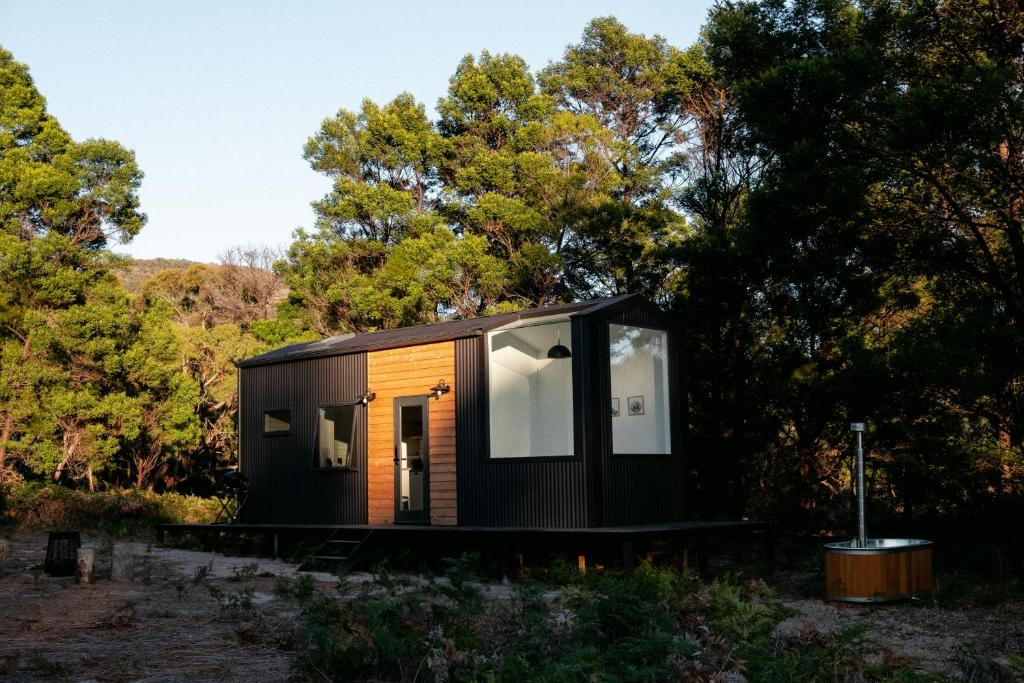 una pequeña casa negra en el bosque en Wild Life Cabin 2 - Grampians, en Halls Gap