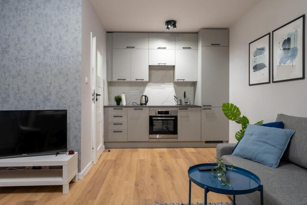 a living room with a gray couch and a kitchen at Apartament Klimatyczny - blisko centrum by Space Apart in Jelenia Góra