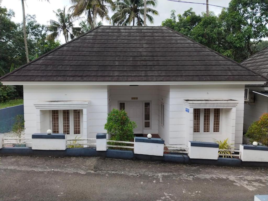 uma casa branca com um telhado preto em Rose villas em Athirappilly