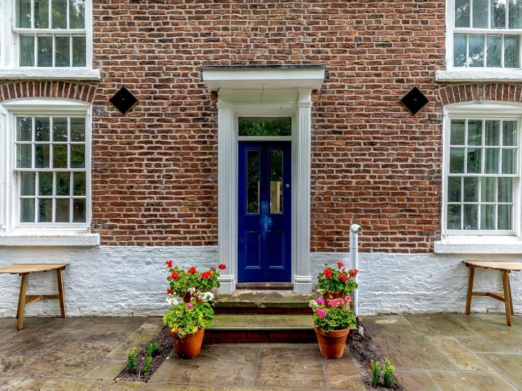 niebieskie drzwi na ceglanym budynku z dwoma doniczkami w obiekcie 1 Bed in Chester 78586 w mieście Chester