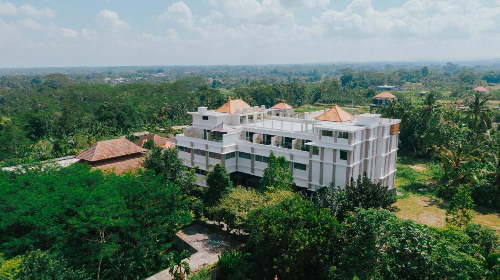 吉安雅Taman Prakerti Bhuana Hotel的树木中白色建筑的空中景观