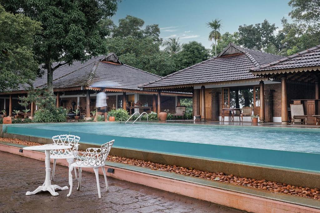 duas cadeiras e uma mesa ao lado de uma piscina em BluSalzz Escapade - Muhamma, Alleppey - Kerala em Alappuzha