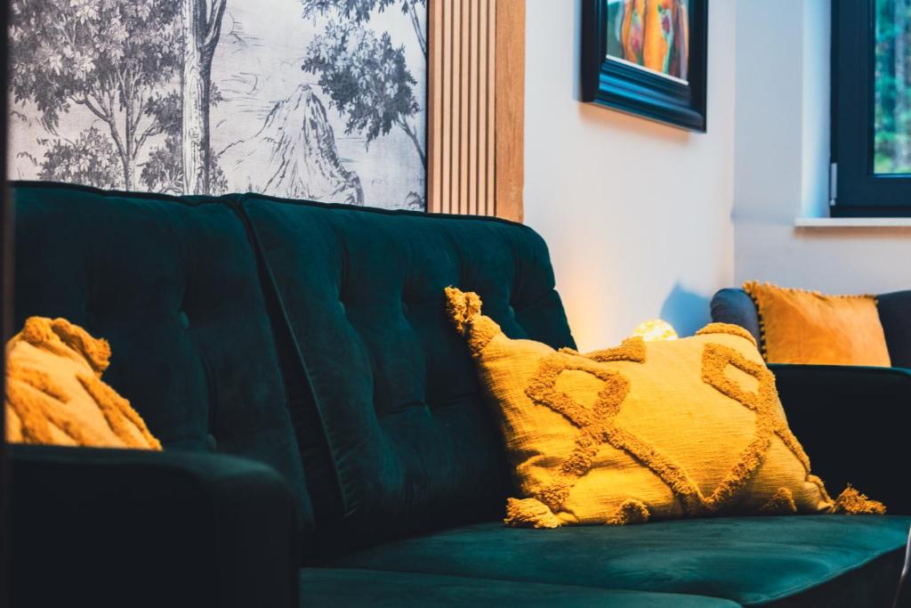 a green couch with a yellow pillow on it at Lubiński Resort in Stężyca