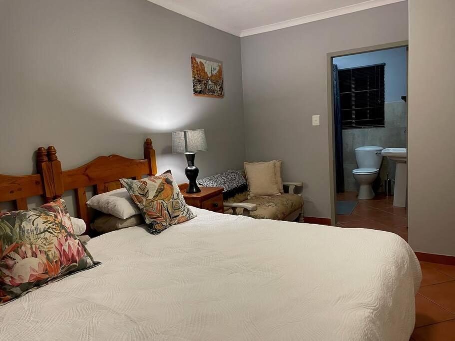 a bedroom with a bed and a chair and a bathroom at Magalies House in Pretoria