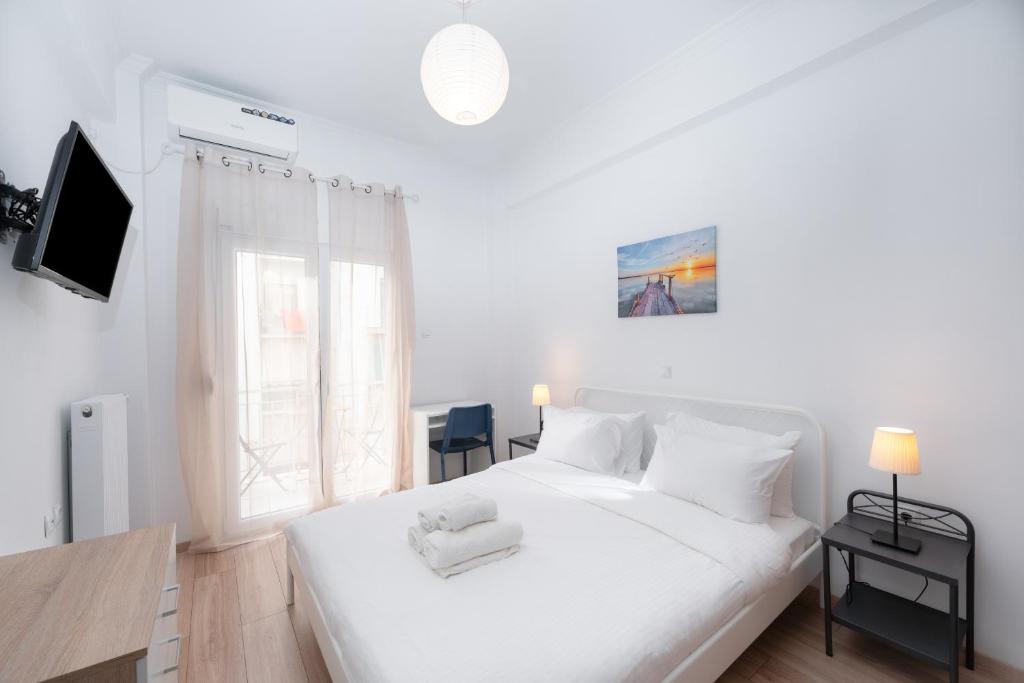 a white bedroom with a white bed and a window at Urban Studio in Koukaki steps to Acropolis in Athens