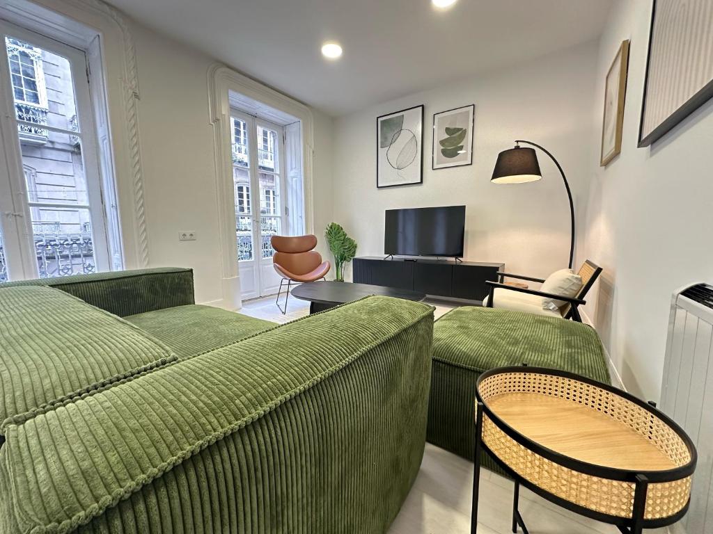 uma sala de estar com um sofá verde e cadeiras em Elegante hogar en el centro em Vigo