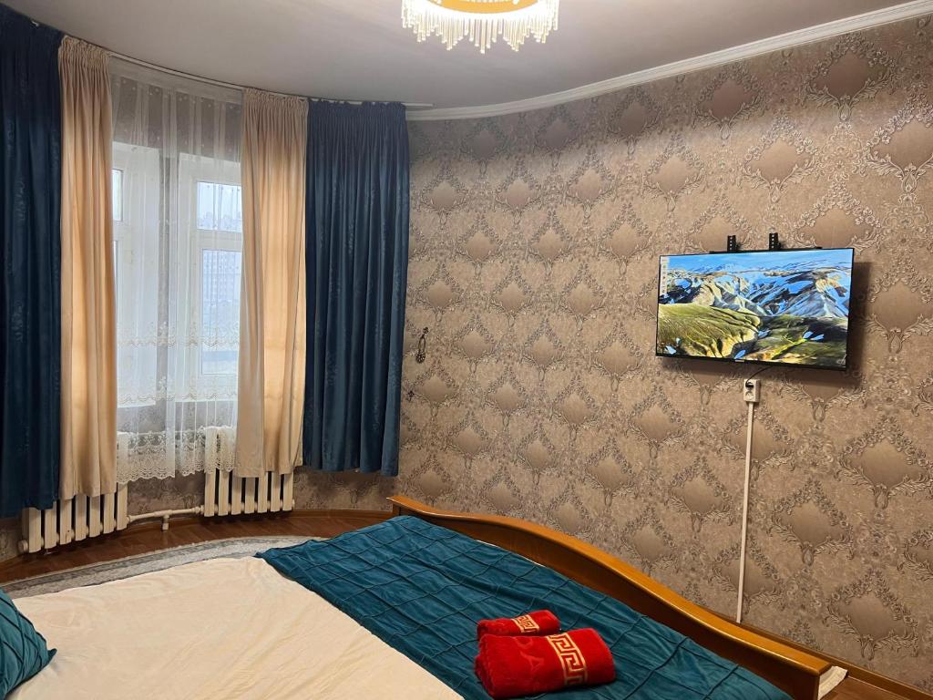 een slaapkamer met een bed en een tv aan de muur bij Apartment on Jeltoksan in Simkent