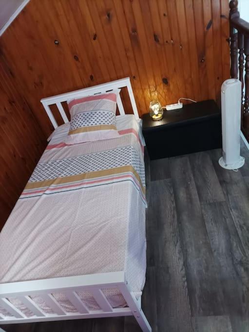 a small bed in a room with a wooden wall at Villa Imelda à saint André la réunion in Le Patelin