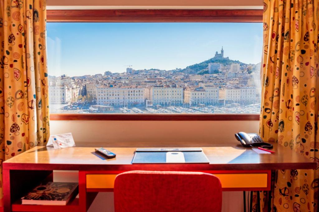 einen Schreibtisch mit einem Fenster mit Stadtblick in der Unterkunft La Residence Du Vieux Port in Marseille