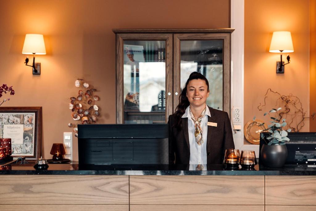 a woman standing at a counter in a room at Gloppen Hotell - by Classic Norway Hotels in Sandane