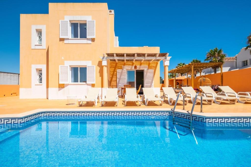a swimming pool with chairs and a house at Villa alhabu in Albufeira