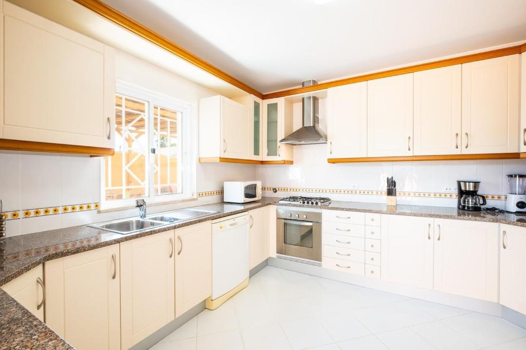 a kitchen with white cabinets and a sink at Villa alhabu in Albufeira