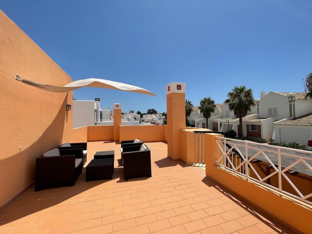 a balcony with chairs and an umbrella on a building at Villa alhabu in Albufeira