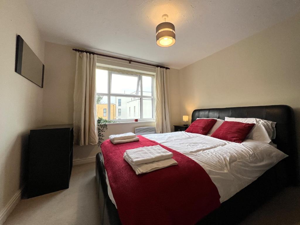 Schlafzimmer mit einem Bett mit roten Kissen und einem Fenster in der Unterkunft Spacious 2BR Flat with Sofa-Bed in Central Reading in Reading