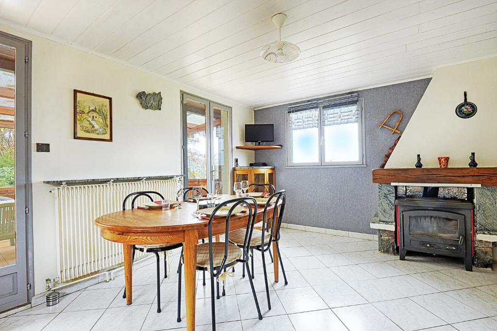 a dining room with a table and chairs and a fireplace at Le Chalet Sous les Sapins - Superbe vue in Rochesson