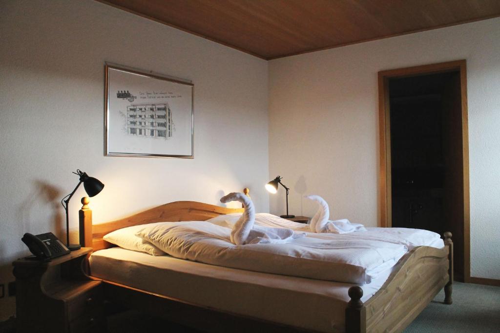 Hotel-Restaurant Krone في Aarberg: اثنين من البجعات جالسين على سرير في غرفة النوم