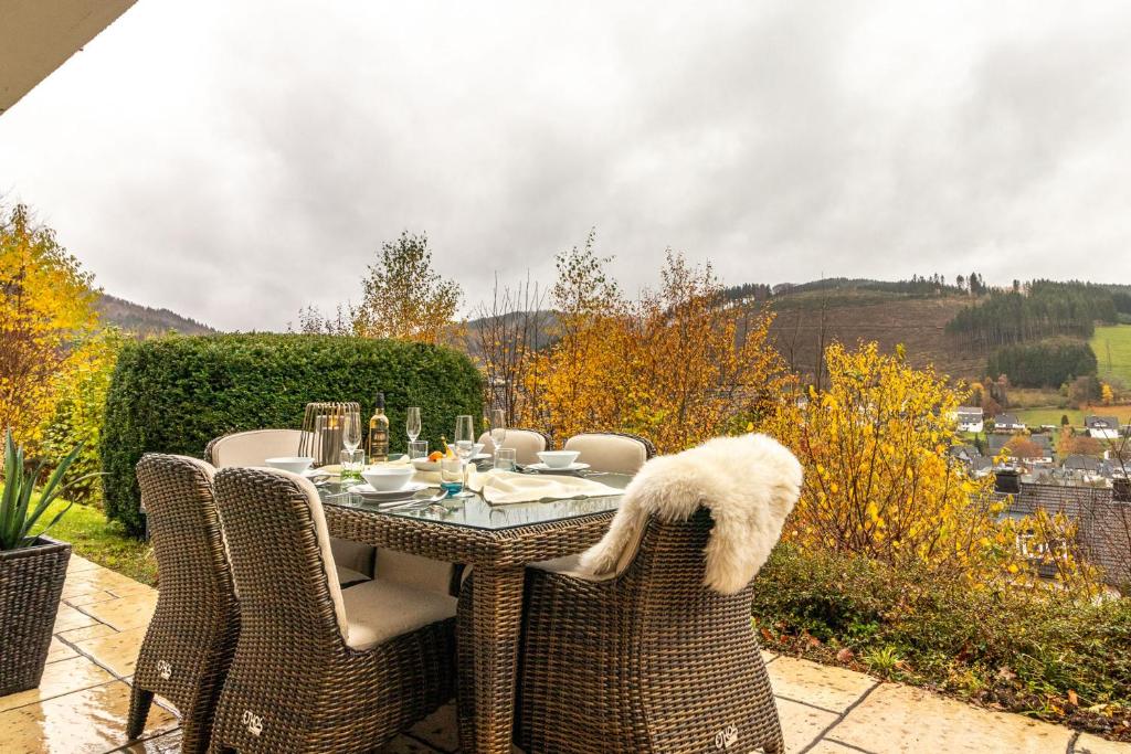 a dining table with wicker chairs on a patio at Hillebachsee in Winterberg