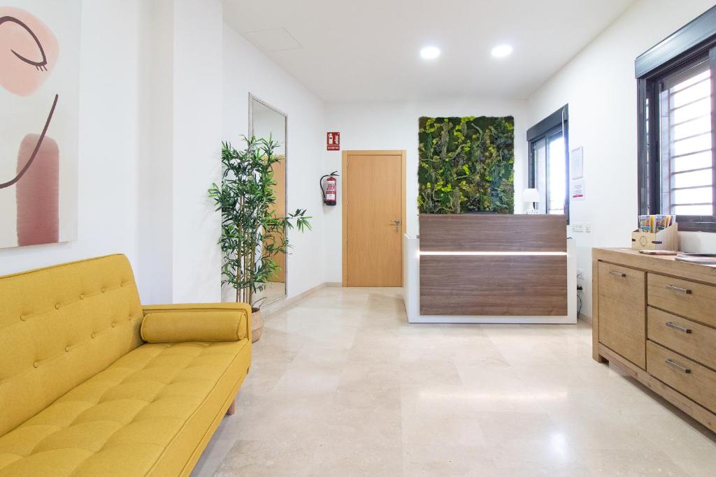 a living room with a yellow couch in front of a door at Hotel Sagunto in Sagunto