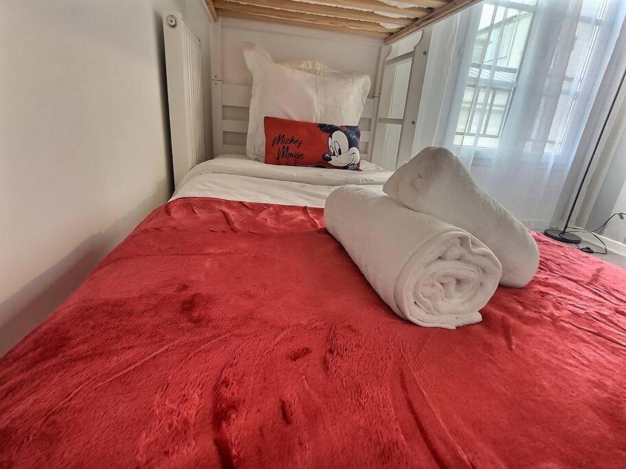 a bed with a red blanket on top of it at Le Nuage d&#39;Arianne*Vale d&#39;Europe *Disney*Paris in Chessy