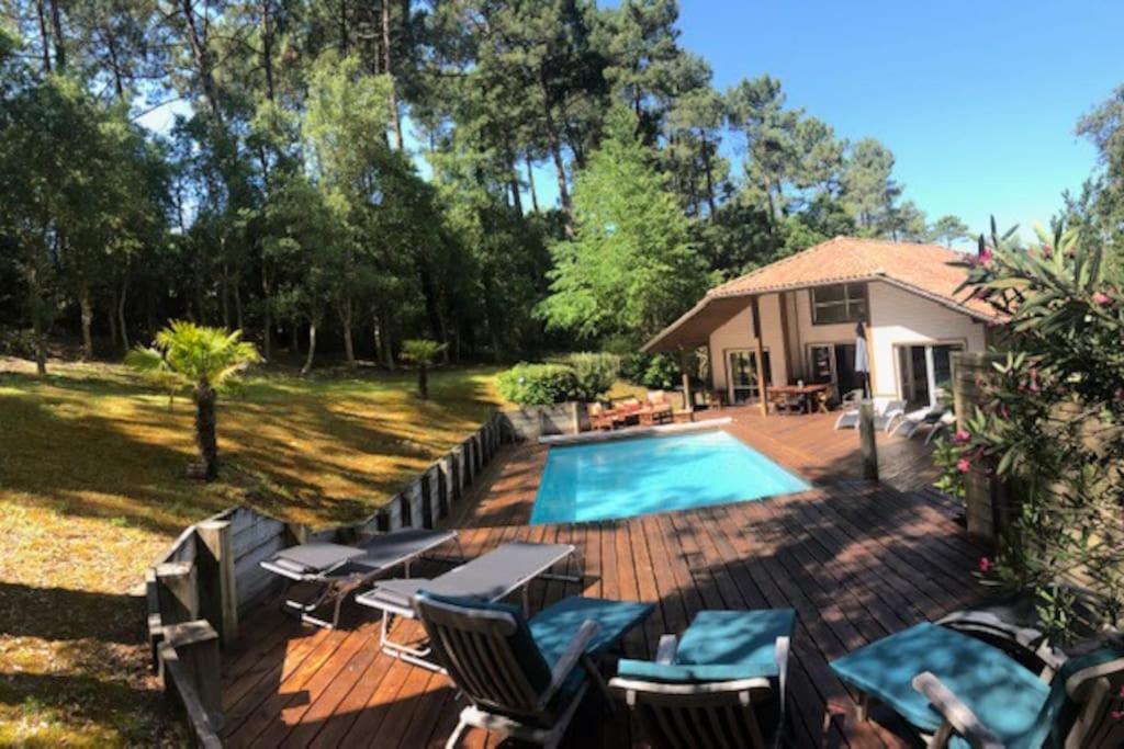 une cour arrière avec une piscine et une maison dans l'établissement Villa avec piscine pétanque ping-pong garage près golf plage, à Moliets-et-Maa