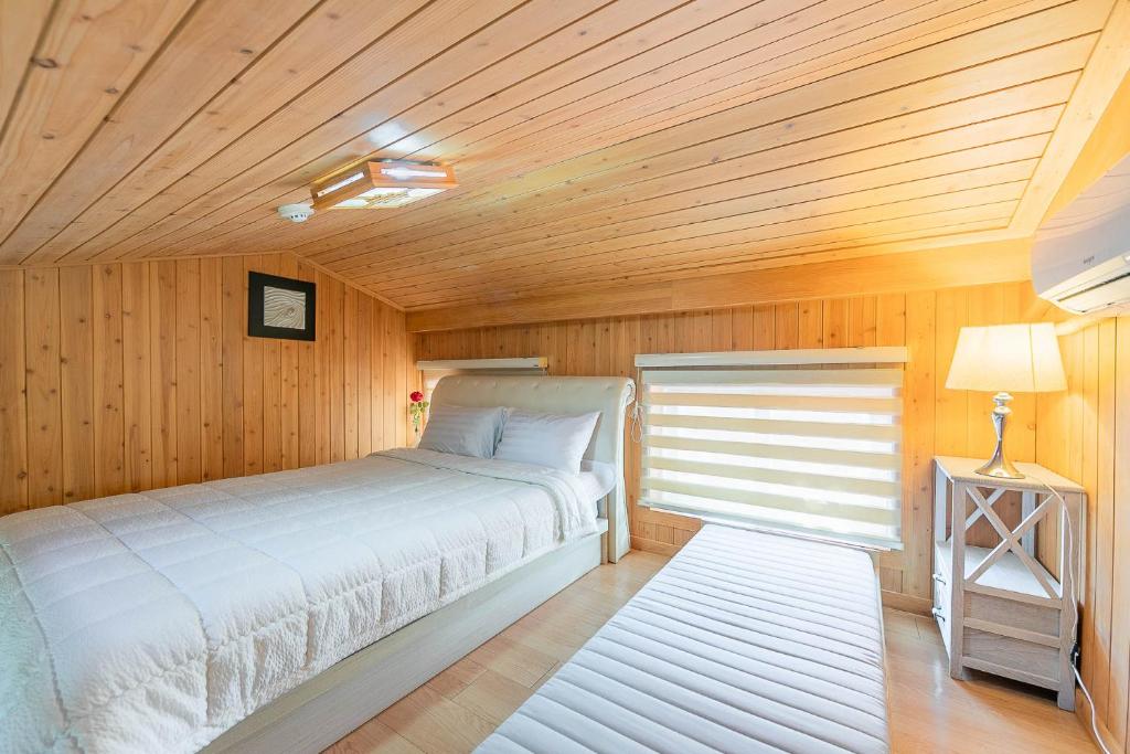 Four Seasons Pension في سون تشون: غرفة نوم بسرير وسقف خشبي
